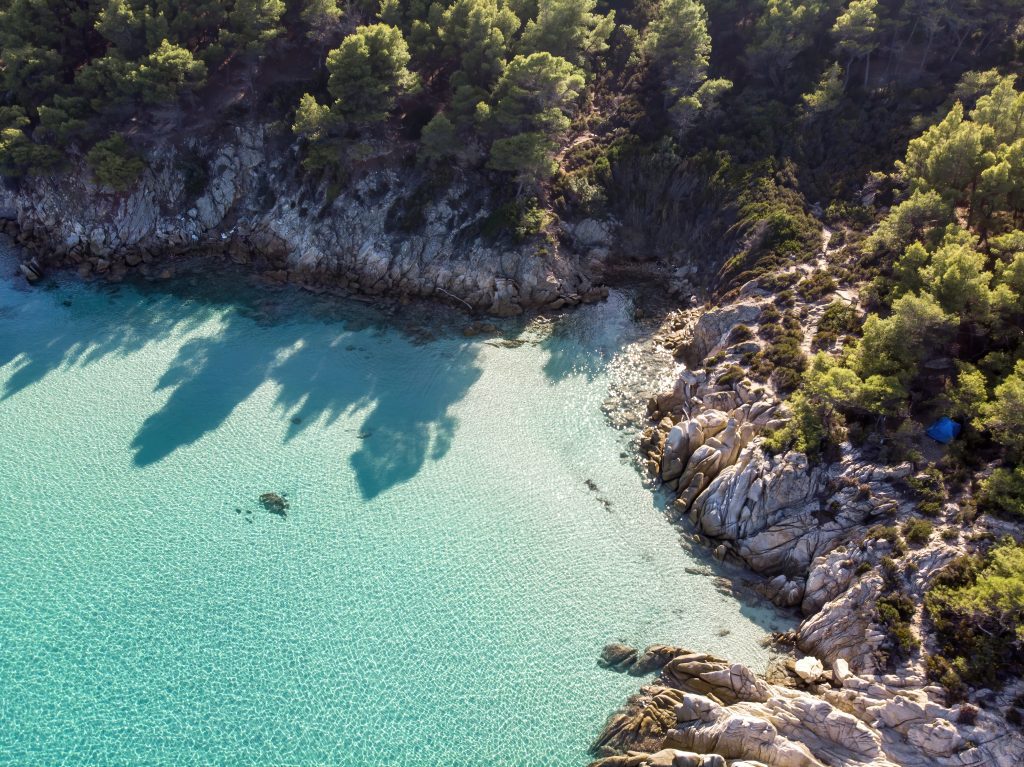 Sail Away to the Most Popular Yacht Charter Destinations in 2024 2 book2sail-aegean sea coast with blue transparent water greenery around rocks bushes trees view from drone greece